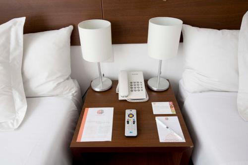 a bed with a table with a phone and two lamps at Tierra Viva Puno Plaza in Puno