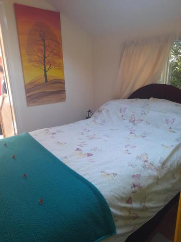 Una cama en un dormitorio con un cuadro en la pared. en Janet Hale Studios, Garden Apartment, en Glastonbury