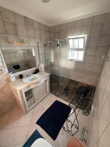 een badkamer met een wastafel, een douche en een spiegel bij Casa #SerJo in São Brás de Alportel