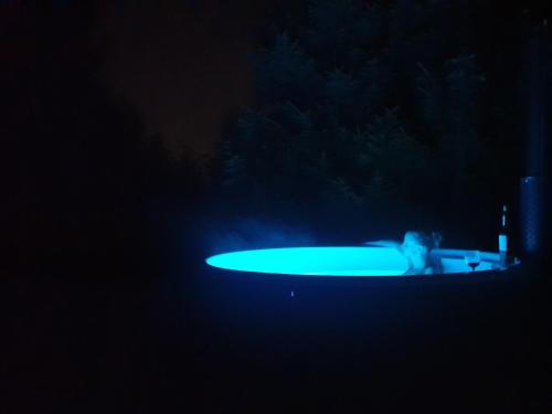 a person in a pool with a surfboard in the dark at Leśne zacisze - dom z kominkiem i balią in Jordanów
