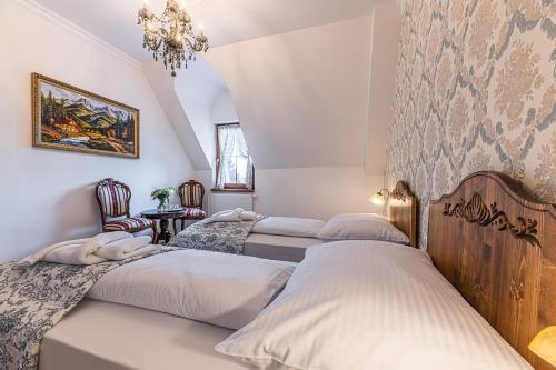 a bedroom with three beds and a chandelier at Hotel Ondava in Stropkov