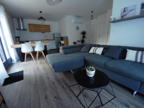 un salon avec un canapé bleu et une table dans l'établissement Gîte à la campagne avec jacuzzi, à Avensan