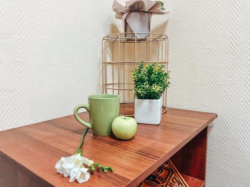 a table with a green coffee cup and a plant at Mini Hotel near Arena City in Kyiv