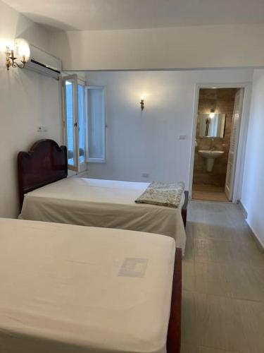 a room with two beds and a bathroom with a sink at Cheerful fully furnished 3 bedroom villa in North Coast in Dawwār Abū Maḩrūs