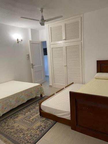 a bedroom with two beds and a ceiling fan at Cheerful fully furnished 3 bedroom villa in North Coast in Dawwār Abū Maḩrūs