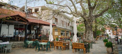 an outdoor cafe with tables and chairs and a tree at Rapsani Panorama Villa in Rapsáni