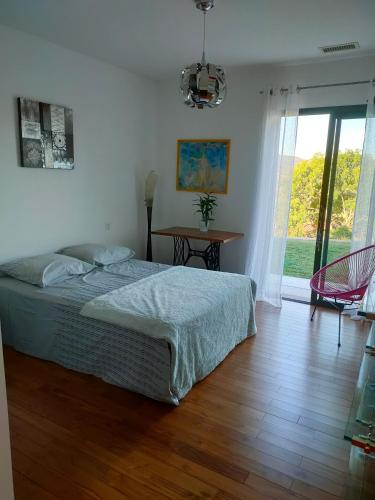 une chambre avec un lit, une table et une fenêtre dans l'établissement Villa Contemporaine Climatisée classée 4 étoiles - Vue panoramique sur la Vallée d'Orb et le Caroux, à Bédarieux