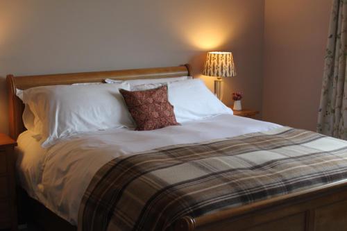 a bed with white sheets and pillows in a bedroom at Heatherbank Guest House in Strontian
