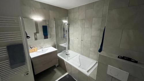 La salle de bains est pourvue d'une baignoire, d'un lavabo et d'une douche. dans l'établissement Châtel - Appartement 4-6 personnes - Les Châlets des Freinets C203, à Châtel