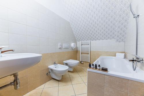 a bathroom with a sink and a tub and a toilet at Hotel Ondava in Stropkov
