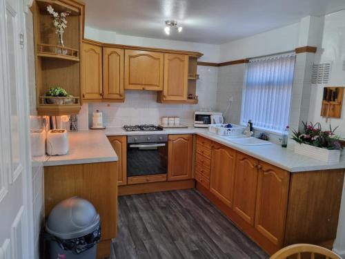 a kitchen with wooden cabinets and a stove top oven at Modern & Elegant Home w/ Netflix and Parking in Leeds