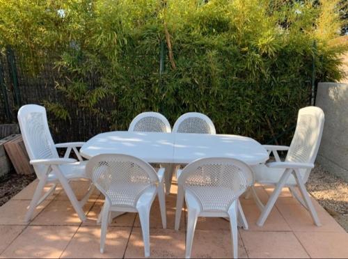 une table blanche entourée de quatre chaises dans l'établissement Rez de villa avec place de parking et vue mer., à La Ciotat