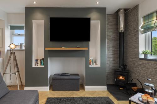 a living room with a fireplace with a tv on the wall at Acorn Cottage in Tenby