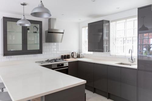 une cuisine avec des armoires noires et des comptoirs blancs dans l'établissement Hampden Apartments - The Louis, à Eton