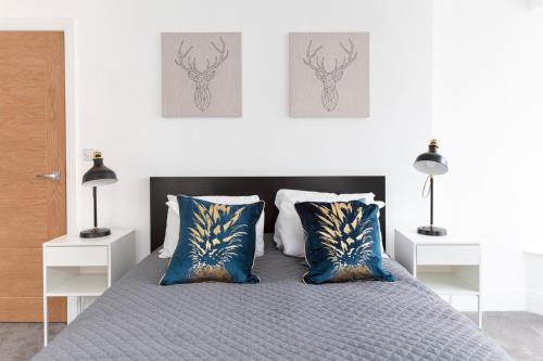 a bedroom with a bed with blue and gold pillows at Hampden Apartments - The Louis in Eton
