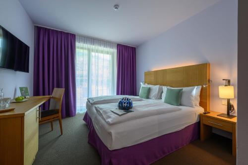 a hotel room with a large bed with purple curtains at Active & Family Hotel Gioiosa in Riva del Garda