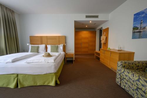 a hotel room with a large bed and a chair at Active & Family Hotel Gioiosa in Riva del Garda