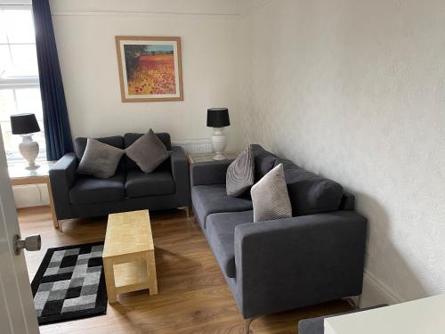 a living room with a black couch and a table at Spacious 4-bed Holiday Home in the heart of Maidstone in Maidstone