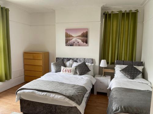 a bedroom with two beds and green curtains at Spacious 4-bed Holiday Home in the heart of Maidstone in Maidstone