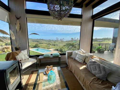 sala de estar con sofá, TV y ventana grande en Hermosa y acogedora parcela cerca de viñas y playa, en Algarrobo