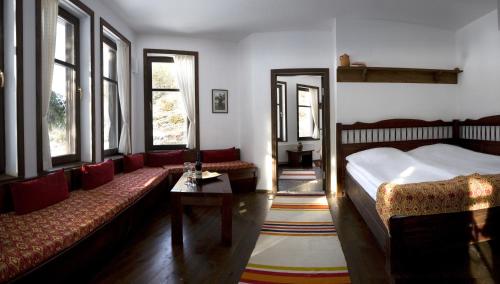 a bedroom with a bed and a couch and windows at Family Hotel Arkan Han in Trigrad
