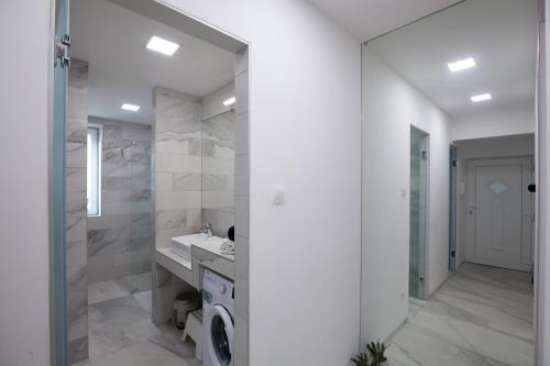 ein weißes Badezimmer mit einem Waschbecken und einem Spiegel in der Unterkunft Stellar Downtown Szeged in Szeged
