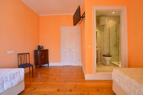 a bedroom with orange walls and a bathroom with a toilet at History House in Corfu Town