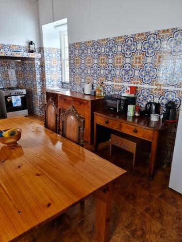 a living room with a wooden table and a wall at Casa da Cruz in Santa Cruz das Flores