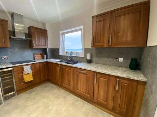 a kitchen with wooden cabinets and a window at Beachfront Penthouse, Largs in Largs