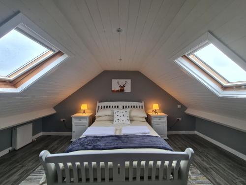 a attic bedroom with a bed and two windows at Kingarrow Cottage in Omagh