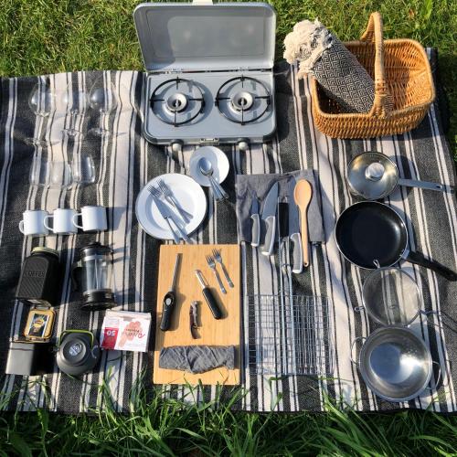 a picnic blanket with utensils and a grill on the grass at Coasters Hideaway boutique Glamping in Brunnby