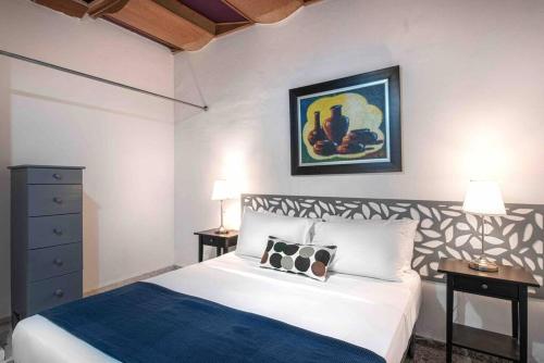 a bedroom with a bed and two tables and a painting at Escape Apartment in Gazcue Close to Colonial Zone in Santo Domingo