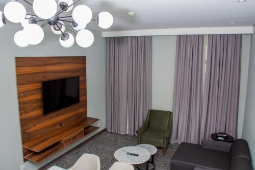 a living room with a television and a couch and chairs at Radisson Lagos Ikeja in Lagos