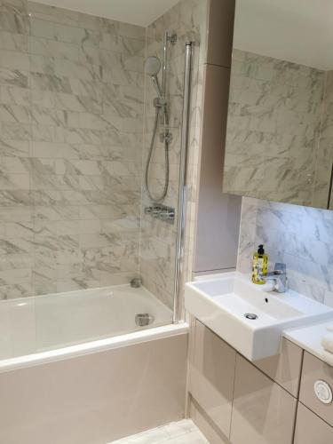 a bathroom with a shower and a sink and a tub at Comfy 1 bed studio 1 minute from Train station in London