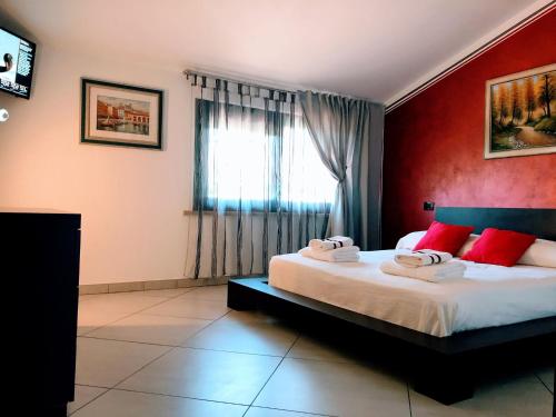 a bedroom with a bed with red walls and a window at Garda Art&Garden in Volta Mantovana