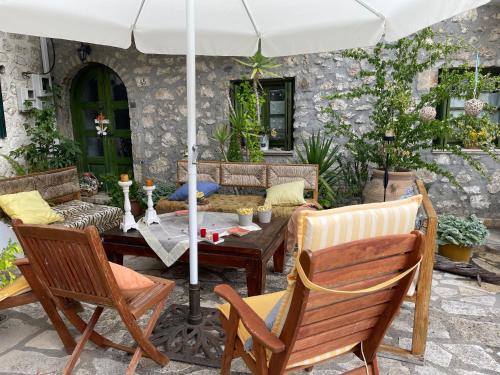 a patio with a table and chairs and an umbrella at Petra Maisonettes in Kariá