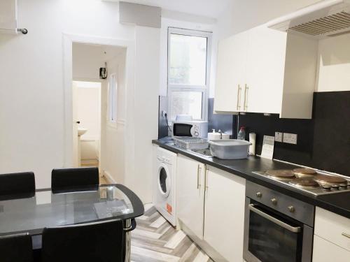 Beautiful 2 Bed Serviced Apartment in Dunbar في دنبار: مطبخ بدولاب أبيض وقمة كونتر أسود