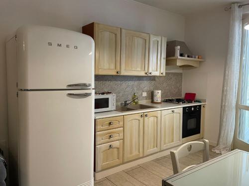 a white refrigerator in a kitchen with wooden cabinets at Aury & Ester Casa Vacanze in Crema