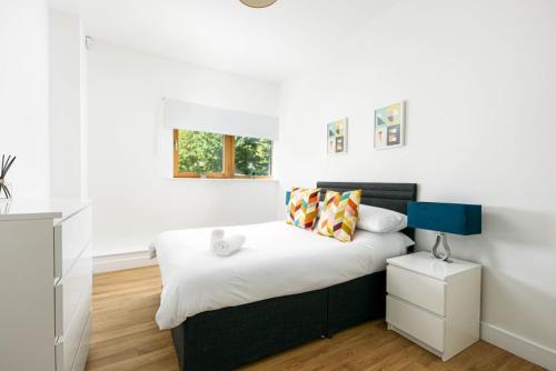 a bedroom with a bed with white sheets and a blue lamp at Lovely 2 bedroom apartment in Central Bristol in Bristol