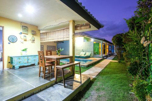un patio al aire libre con mesa de madera y sillas en Blue Coco, en Keramas