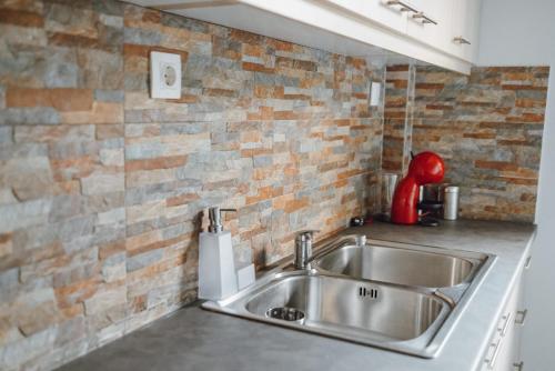 a kitchen with a sink and a brick wall at THALASSA ALMYROS APARTMENTS in Almirón