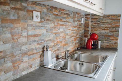 kuchnia ze zlewem i ceglaną ścianą w obiekcie THALASSA ALMYROS APARTMENTS w mieście Almirón