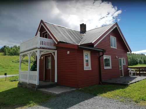 a small red house with a porch on a field at Sommerstue Hessdalen in Ålen