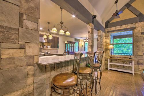 a kitchen with a stone wall and bar stools at Dragon Castle with Secret Passage, Dock, and Hot Tub in Camdenton