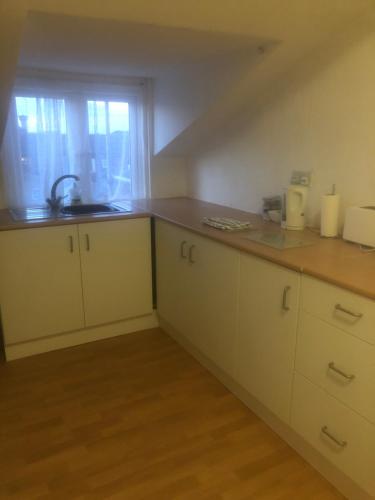 a kitchen with white cabinets and a sink and a window at The Mayfair Hotel in Great Yarmouth