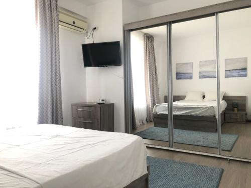 a bedroom with a mirror and a bed and a television at Orange Onix Apartaments in Bucharest