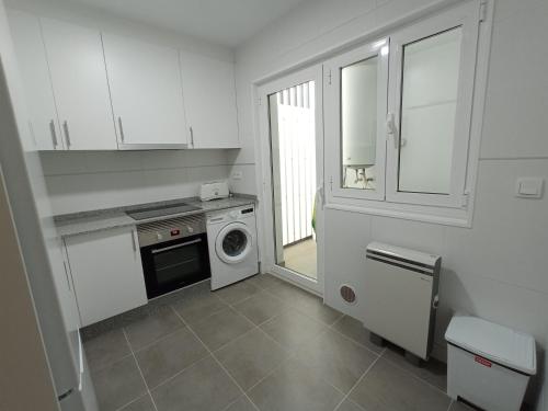 a white kitchen with a washing machine and a washer at Palmeiro in Jove