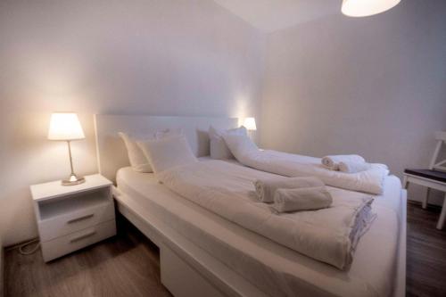 ein weißes Bett mit weißer Bettwäsche und Kissen darauf in der Unterkunft Frische Brise 10.01 in Cuxhaven
