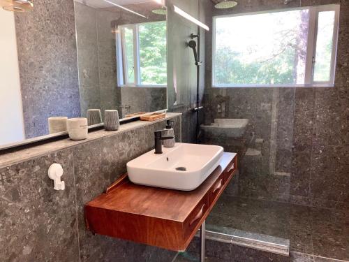 a bathroom with a sink and a mirror and a shower at Enchanting country home with backyard hotspring in Laugaras