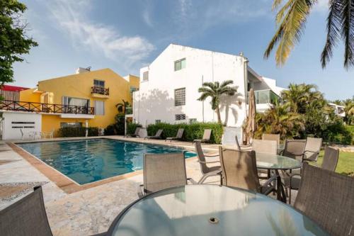 a patio with a table and chairs and a swimming pool at VILLA CHLOE. Modern 4 rooms house with pool in Cancún